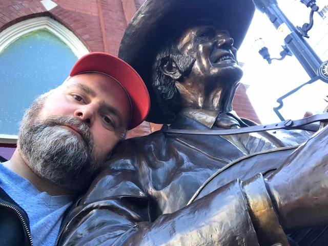 Leaning on a bronze cowboy statue
